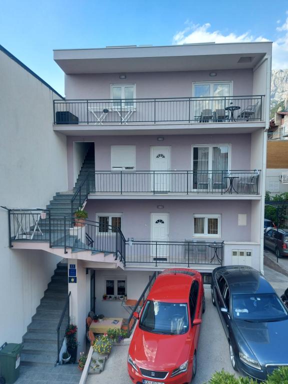 a red car parked in front of a white house at City Apartments Nada in Makarska