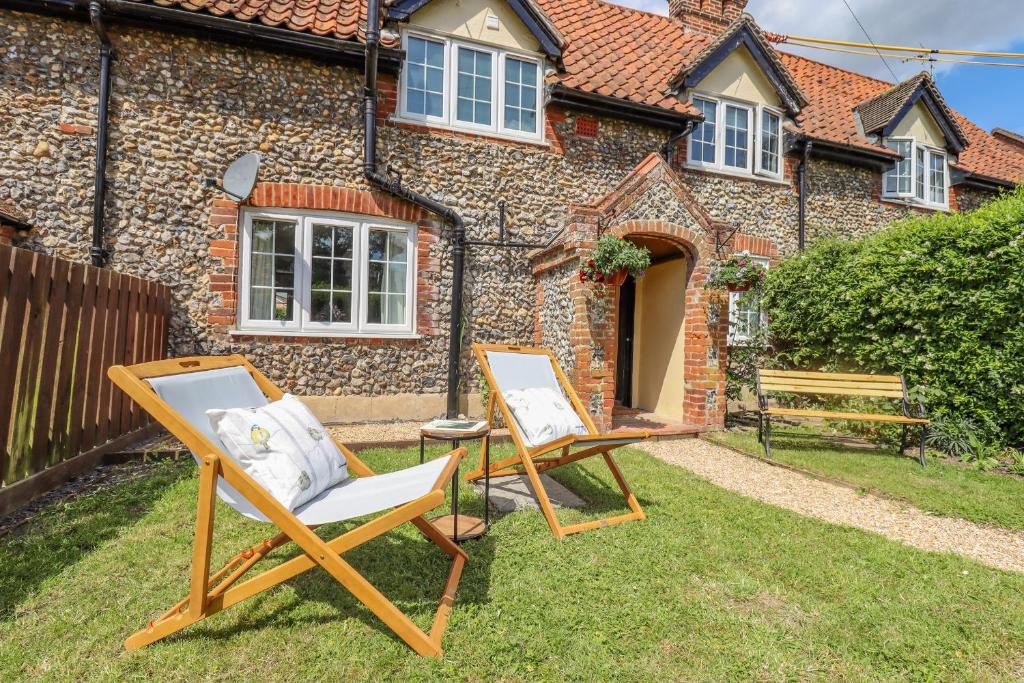 two lawn chairs in front of a house at Bluebird Cottage in Higham