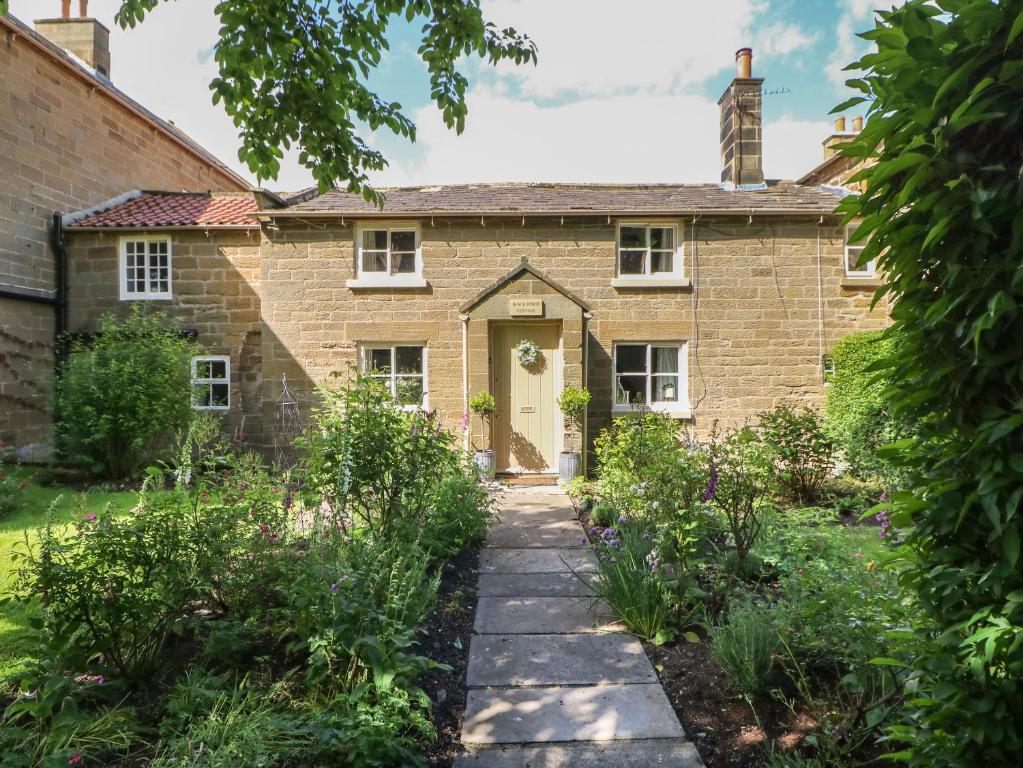 an old brick house with a yellow door at Black Horse Cottage in Northallerton