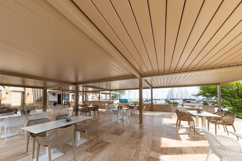 バラトンケネシェにあるBalatonfői Yacht Clubの大きな天井のレストラン(テーブル、椅子付)