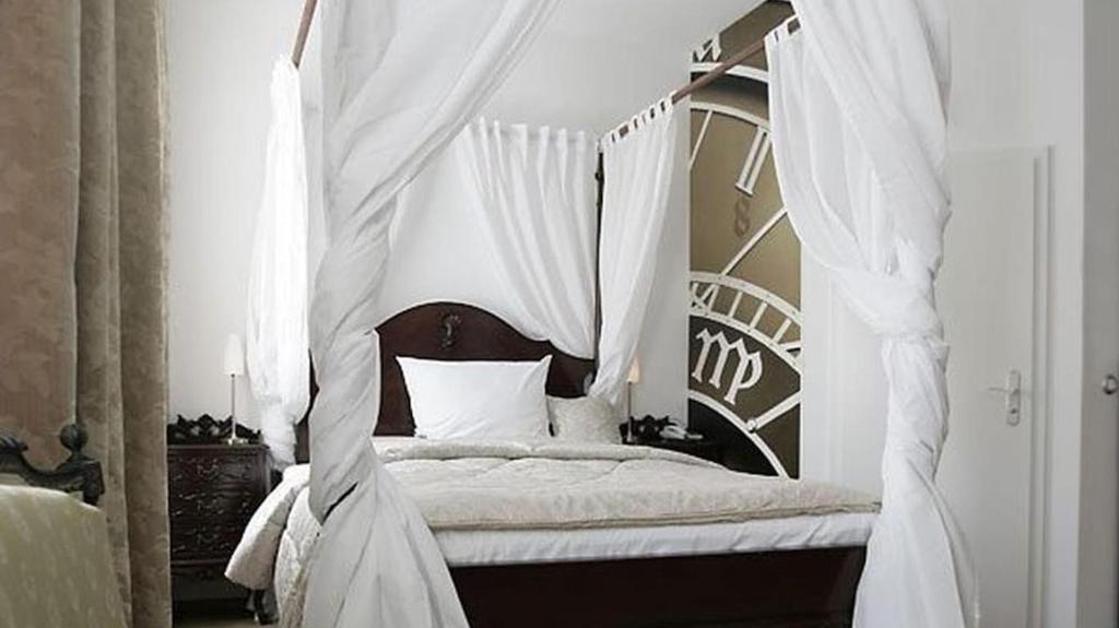 a bedroom with a canopy bed with white curtains at HIP Hotel in Heidelberg