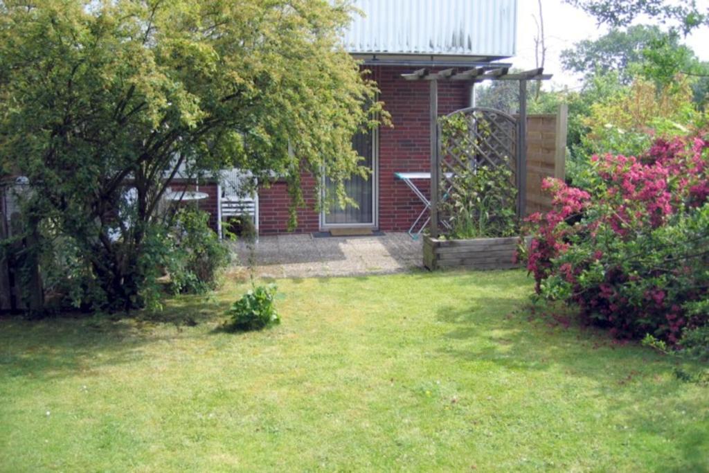 einen Hof mit einem Backsteinhaus mit einem Baum und Blumen in der Unterkunft Flurstraße 10, Whg. 1 in Wyk auf Föhr