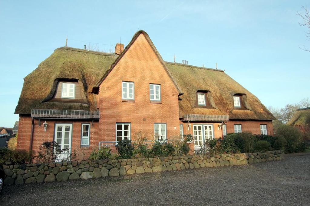 a large red brick house with a thatched roof at Doerpstraat 9_ Whg_ 3 in Wyk auf Föhr