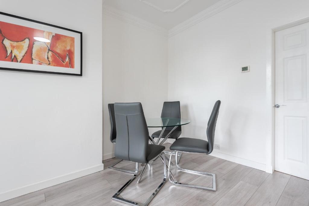 a dining room with a glass table and chairs at Hilltown Apartment in Dundee
