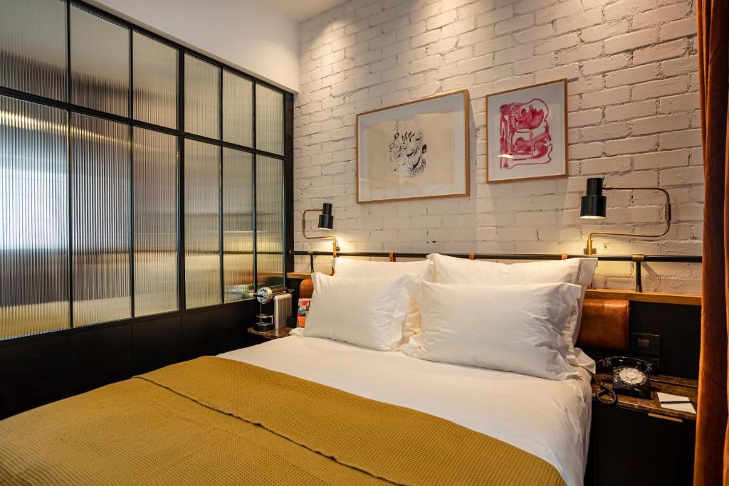 a bedroom with a large bed and a brick wall at Backstage Hotel - an Atlas Boutique Hotel in Tel Aviv