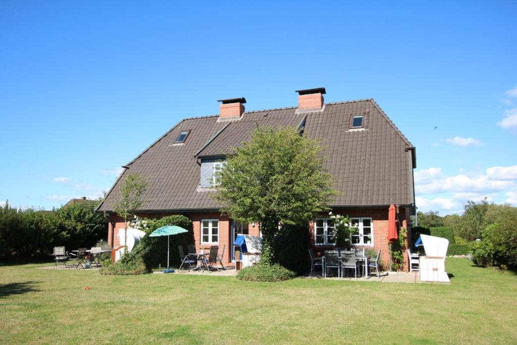 a house with a large roof on a grass field at Karkstieg 6_ Whg_ 2_ Vogtum in Wrixum