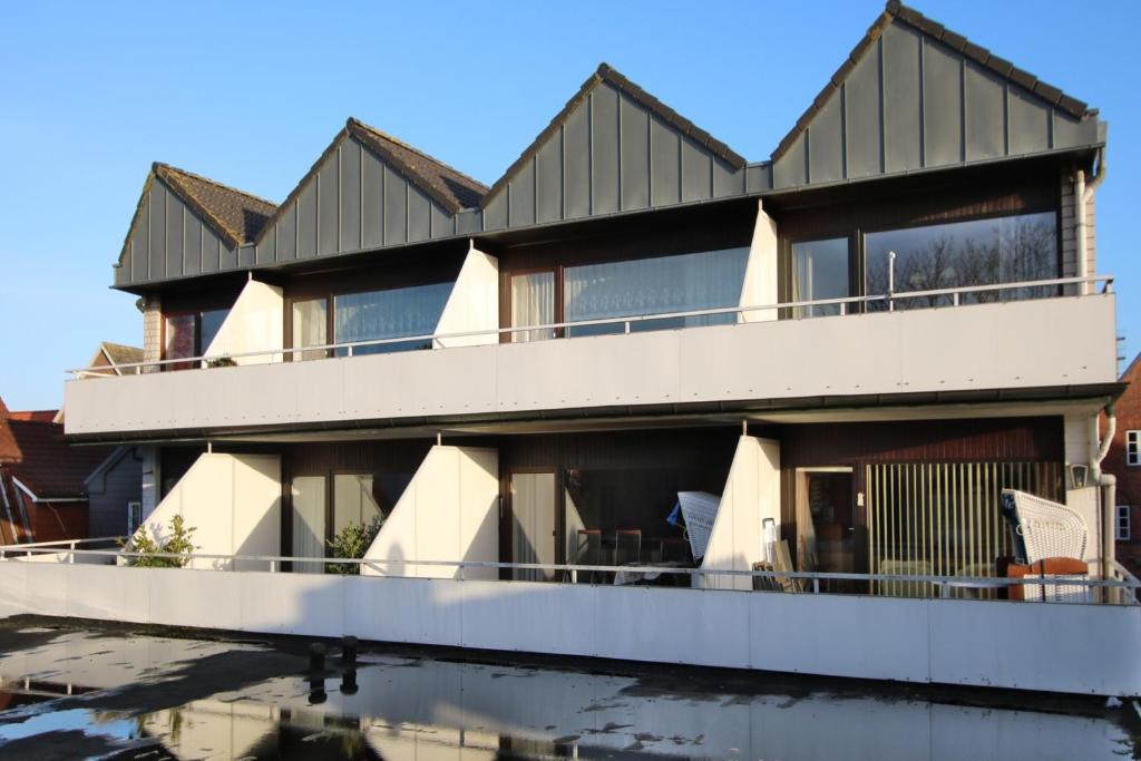 une maison avec balcon et réflexion dans l'eau dans l'établissement Gro_e Stra_e 19_ Whg_ 1, à Wyk auf Föhr