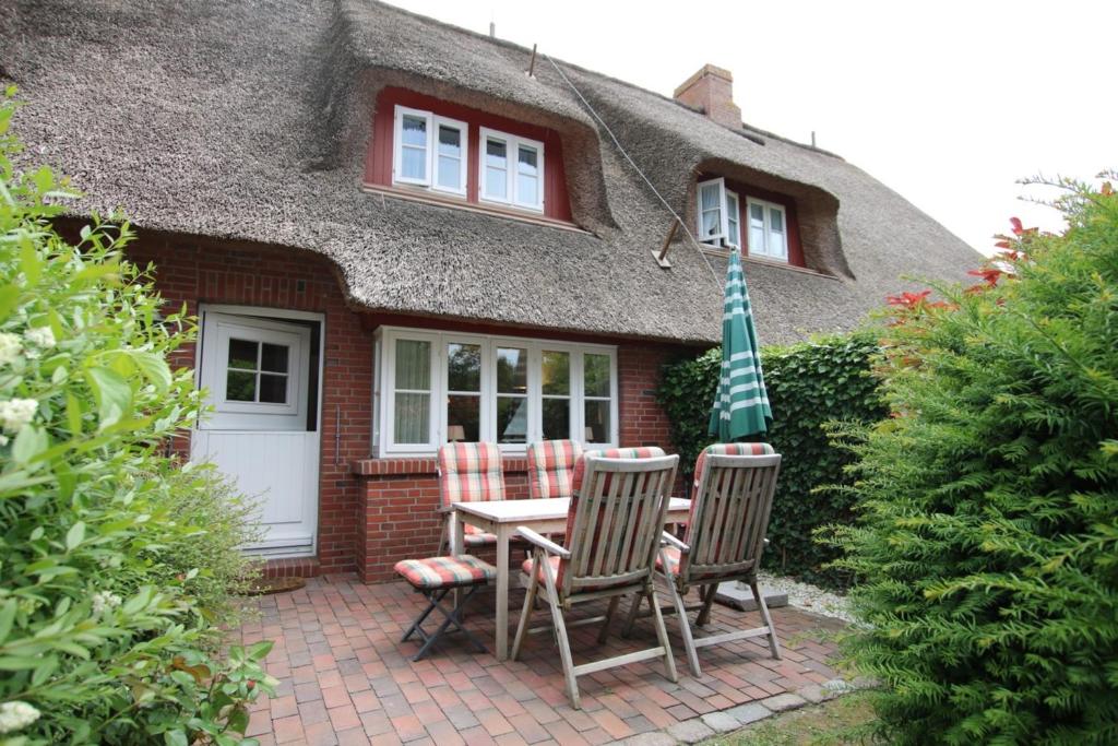 a house with a table and chairs and an umbrella at Ohl Doerp 22 Pastoratshof_ Haus 3 in Wrixum