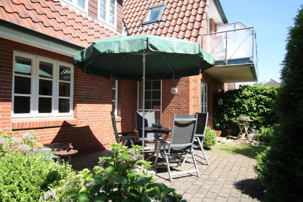eine Terrasse mit einem Tisch und Stühlen unter einem Sonnenschirm in der Unterkunft Rungholtstraße 3c, Whg. 2 in Wyk auf Föhr