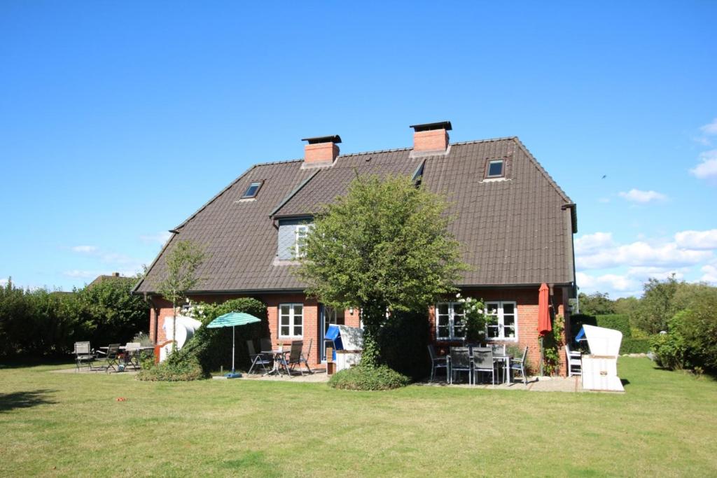 uma casa com um grande telhado num campo de relva em Karkstieg 6_ Whg_ 1_ Vogtum em Wrixum