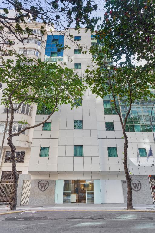 a tall white building with trees in front of it at Windsor Martinique Copacabana in Rio de Janeiro