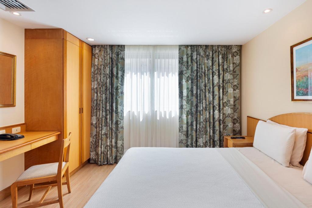 a hotel room with a bed and a desk and a window at Windsor Martinique Copacabana in Rio de Janeiro