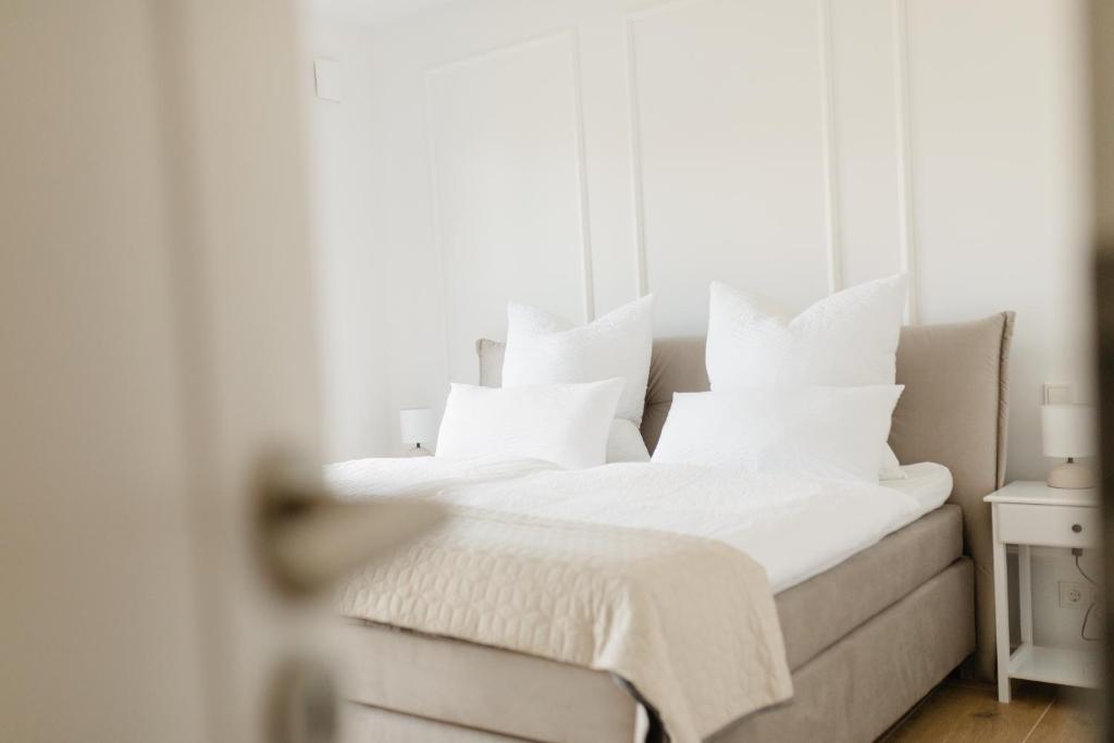 una camera da letto con un letto con cuscini bianchi di Küsten Suite Nord - direkte Wasserlage, Terrasse, 70qm a Greetsiel
