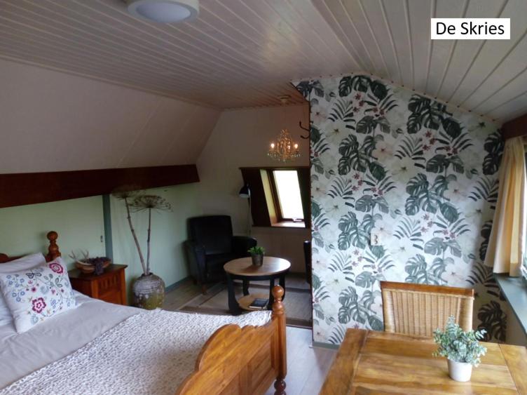 a bedroom with a bed and a table in a room at B&B De Flecht - De Skries in Nijega