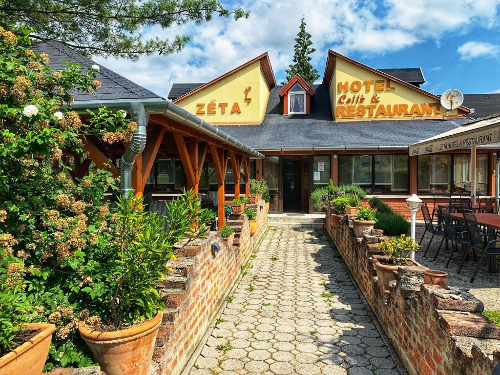 a hotel building with plants in front of it at Hotel Zéta in Lenti