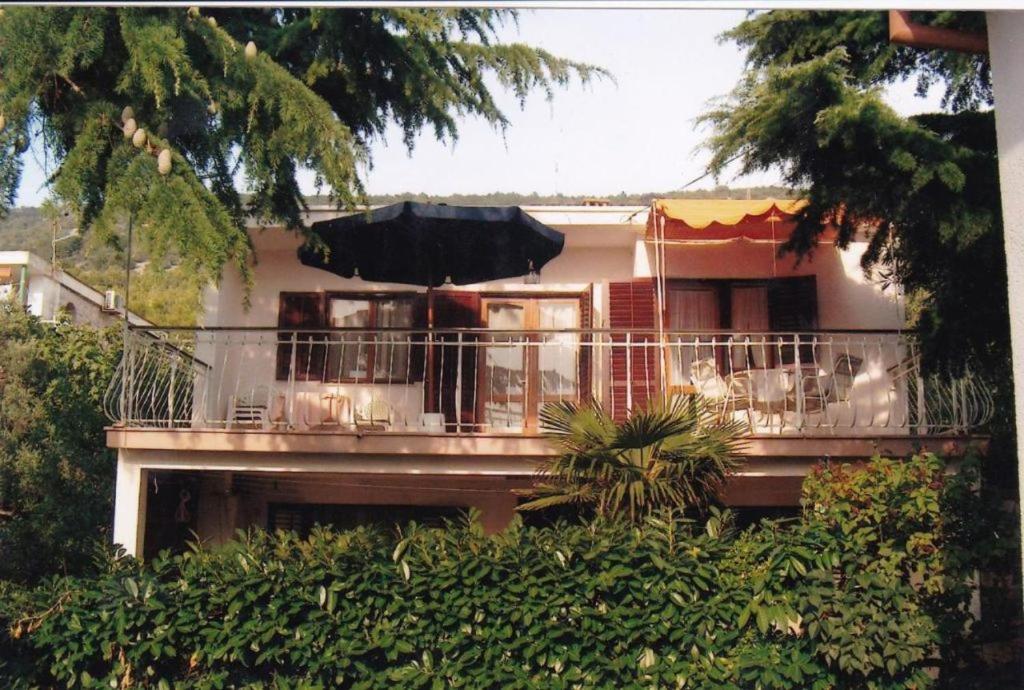 een huis met een balkon met een paraplu erop bij Family apartment with terrace in Cres