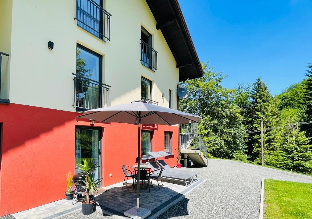 a patio with a table and an umbrella in front of a building at Apartamenty Carpe Diem in Ustroń