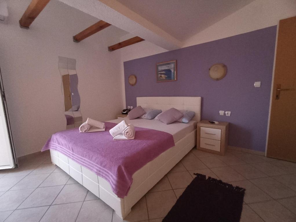 una camera da letto con un grande letto con pareti viola di Apartments Dario a Pag