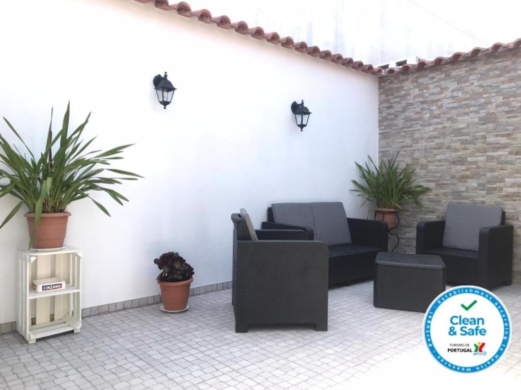 un patio avec des canapés et des plantes en pot ainsi qu'un panneau indiquant la propreté dans l'établissement Casa dos Capinha, à Caldas da Rainha