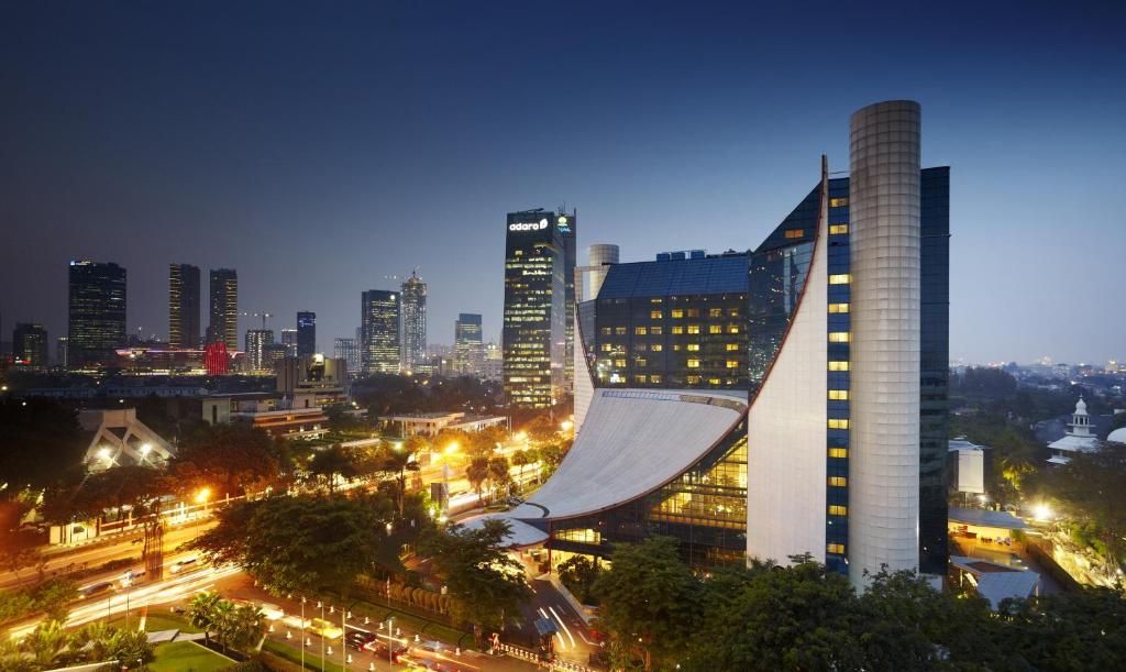 a city skyline at night with a tall building at Gran Melia Jakarta in Jakarta