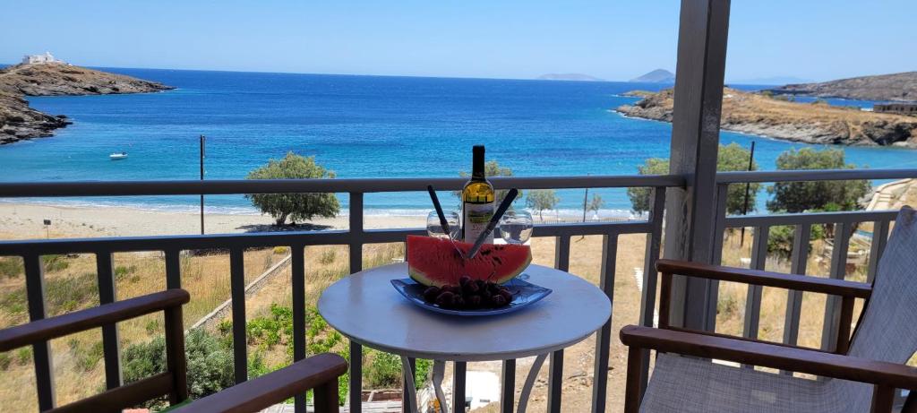 a table with a bottle of wine and fruit on a balcony at House on the Beach 1st Floor one room apartment in Kithnos