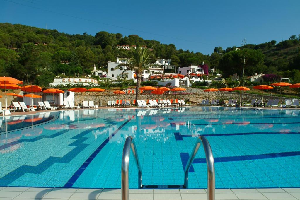una grande piscina con sedie e ombrelloni di Residence Cala Di Mola a Porto Azzurro