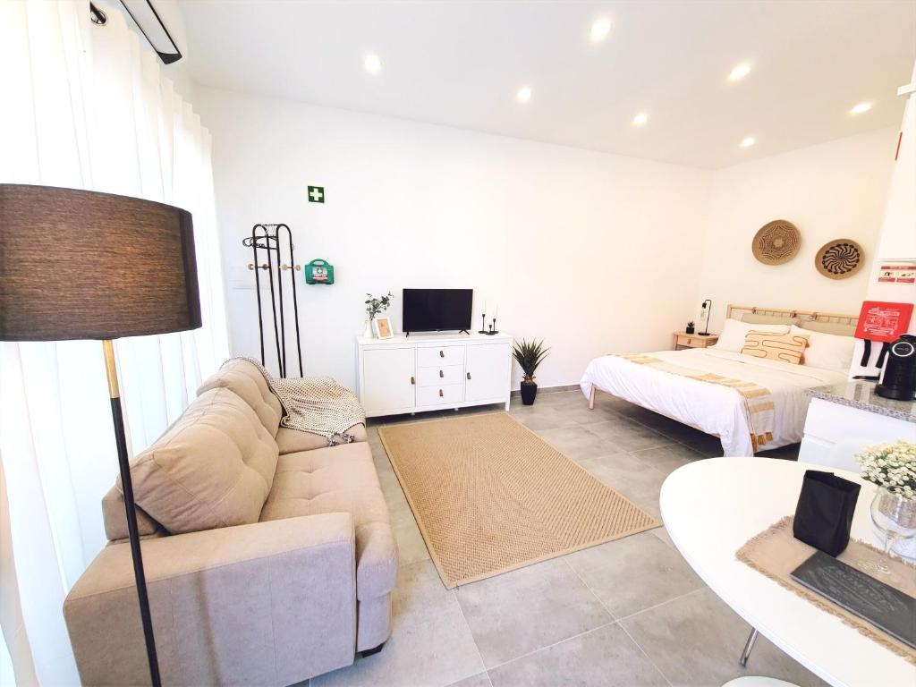 ein Wohnzimmer mit einer Couch und einem Bett in der Unterkunft MF Terceira - Superior Boutique Studio in Praia da Vitória