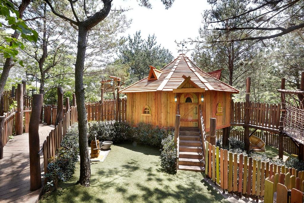 a wooden play house in a yard with a fence at The Shilla Jeju in Seogwipo