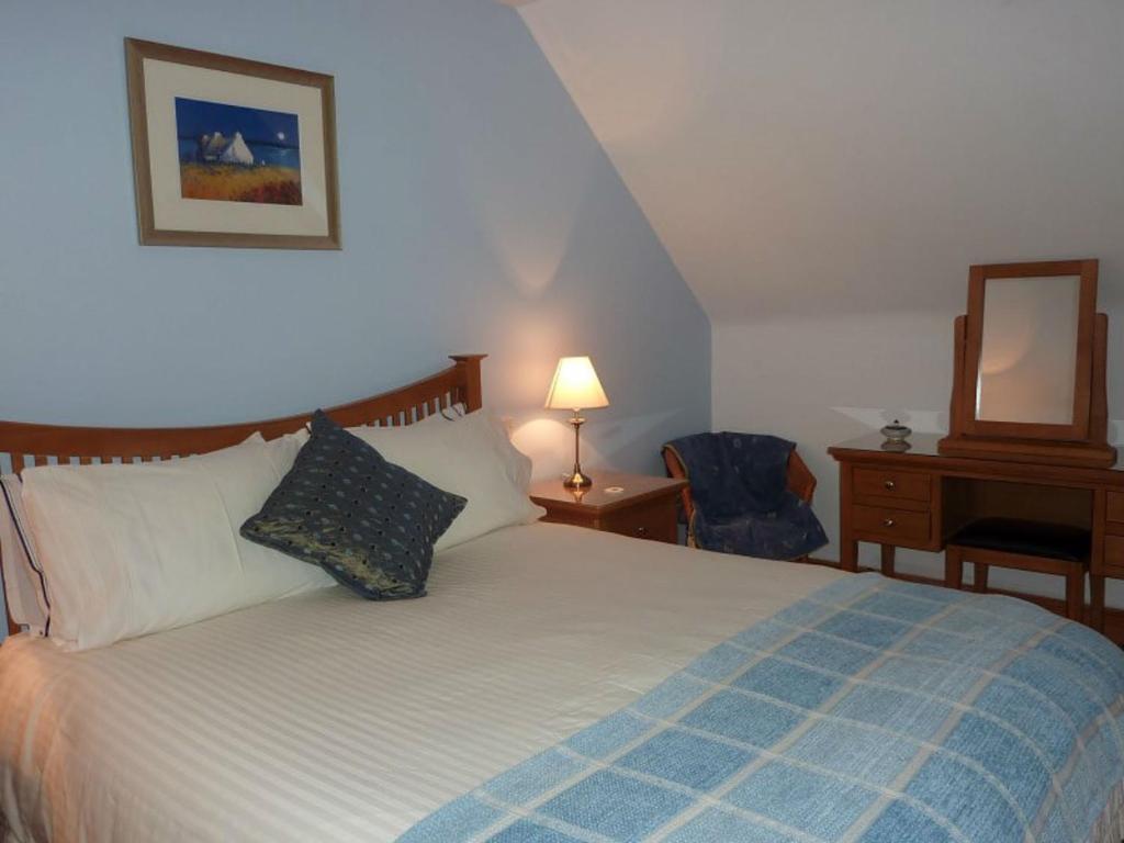 a bedroom with a bed and a desk and a mirror at Taigh Geal in Stornoway