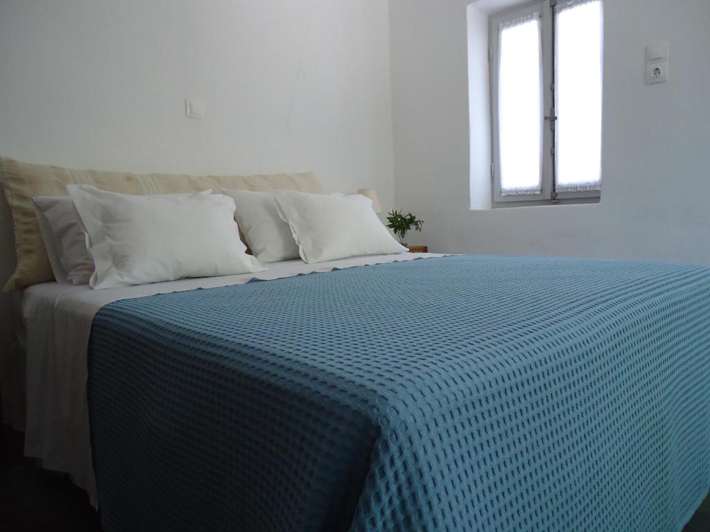 un letto con piumone blu e bianco e una finestra di Aνεξάρτητη παραδοσιακή πέτρινη κατοικία a Kórinthos