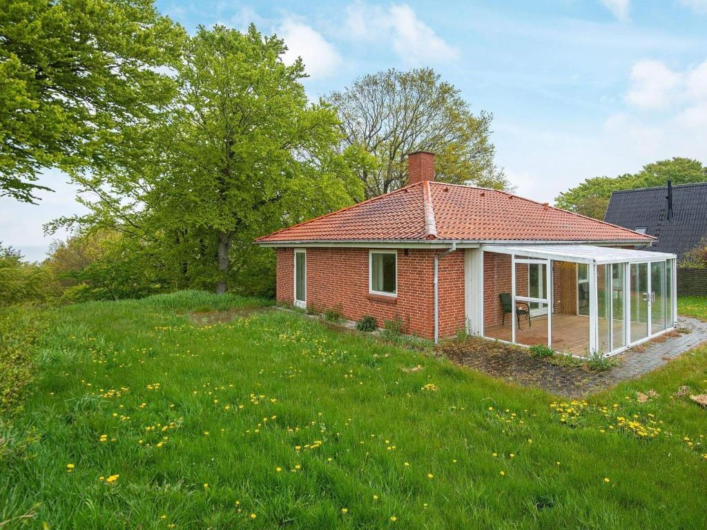 a small red brick house in a field of grass at Serene Seaside Retreat at Hegedal-By Traum in Glesborg