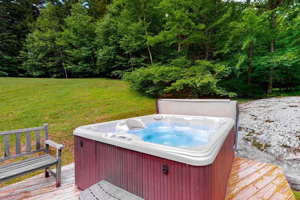 a hot tub sitting on a deck next to a bench at Higgins Lodge in Warren