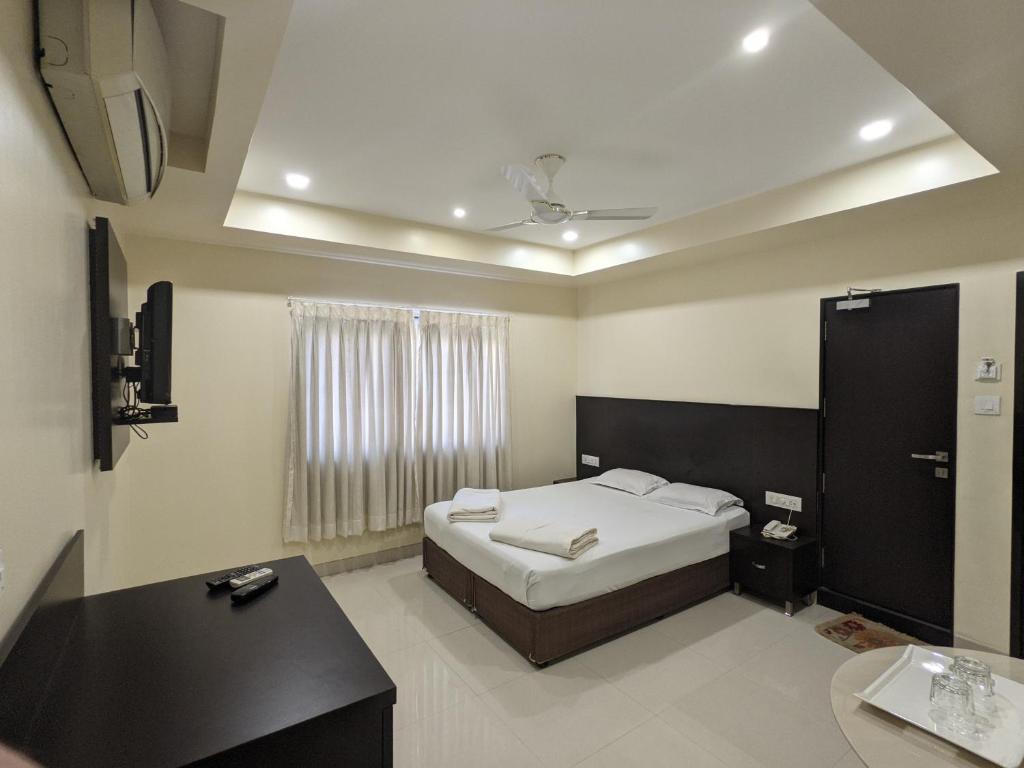 a bedroom with a bed and a desk and a tv at Hotel Sri Kamal International in Solapur
