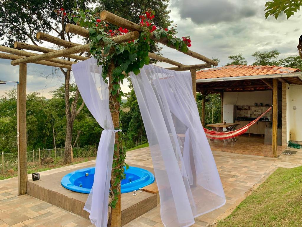 a pergola with white curtains next to a pool at Suíte Vista do Lago - Casa de Temporada em Corumbá in Alexânia