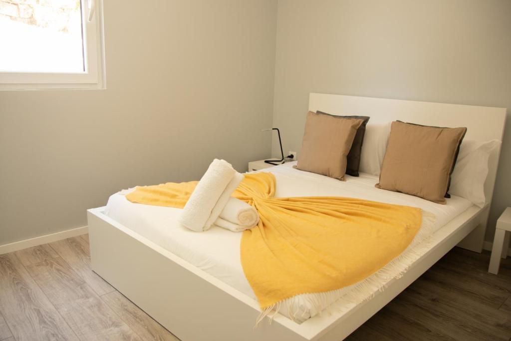 ein weißes Bett mit einer gelben Decke drauf in der Unterkunft Apartamentos do Parque in Vila Real