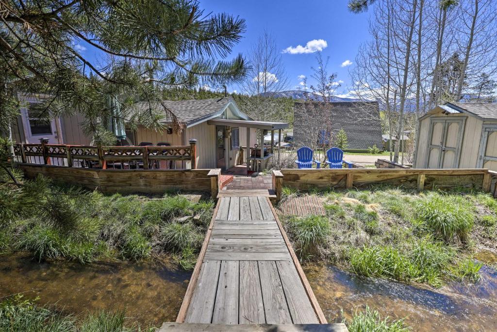 Grand Lake Home with Fireplace, Deck, Mountain Views في غراند ليك: جسر خشبي يؤدي إلى منزل ذو كراسي زرقاء