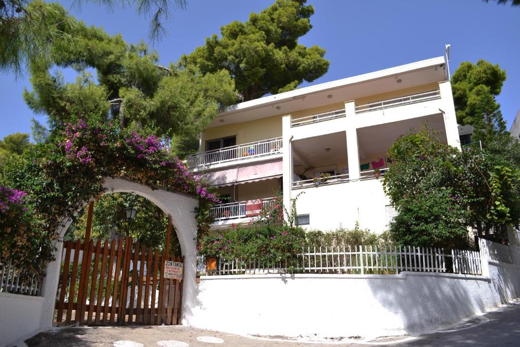 a white building with a gate and flowers at Zontanos Studios & Apartments in Poros