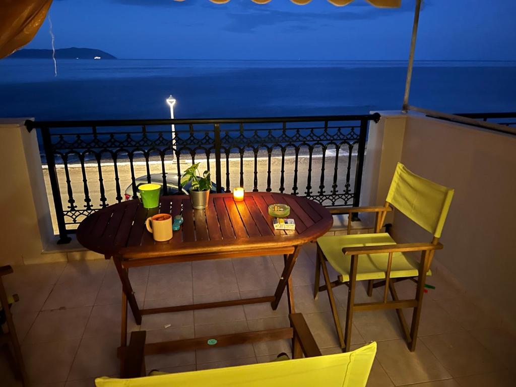a wooden table and chairs on a balcony at night at Cosy Apartment by the water, Agia Pelagia in Agia Pelagia