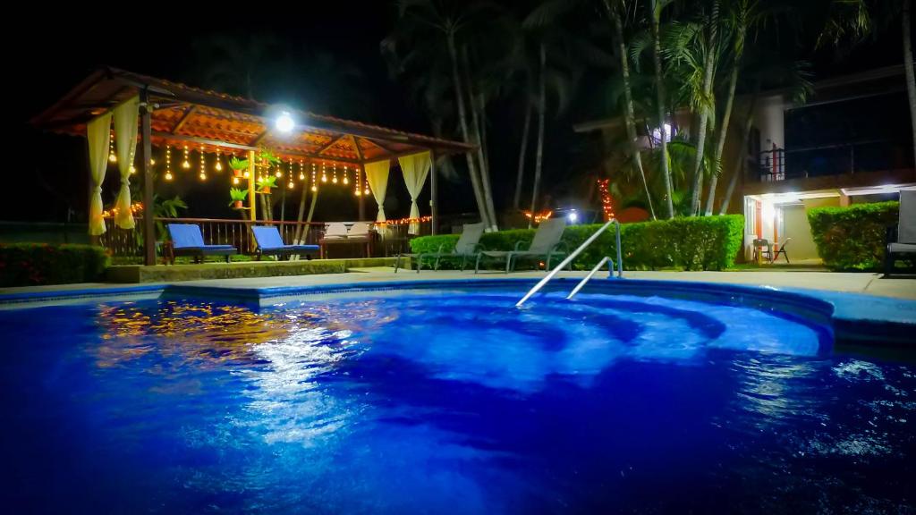 a swimming pool at night with a house at Hotel & Villas Huetares in Playa Hermosa