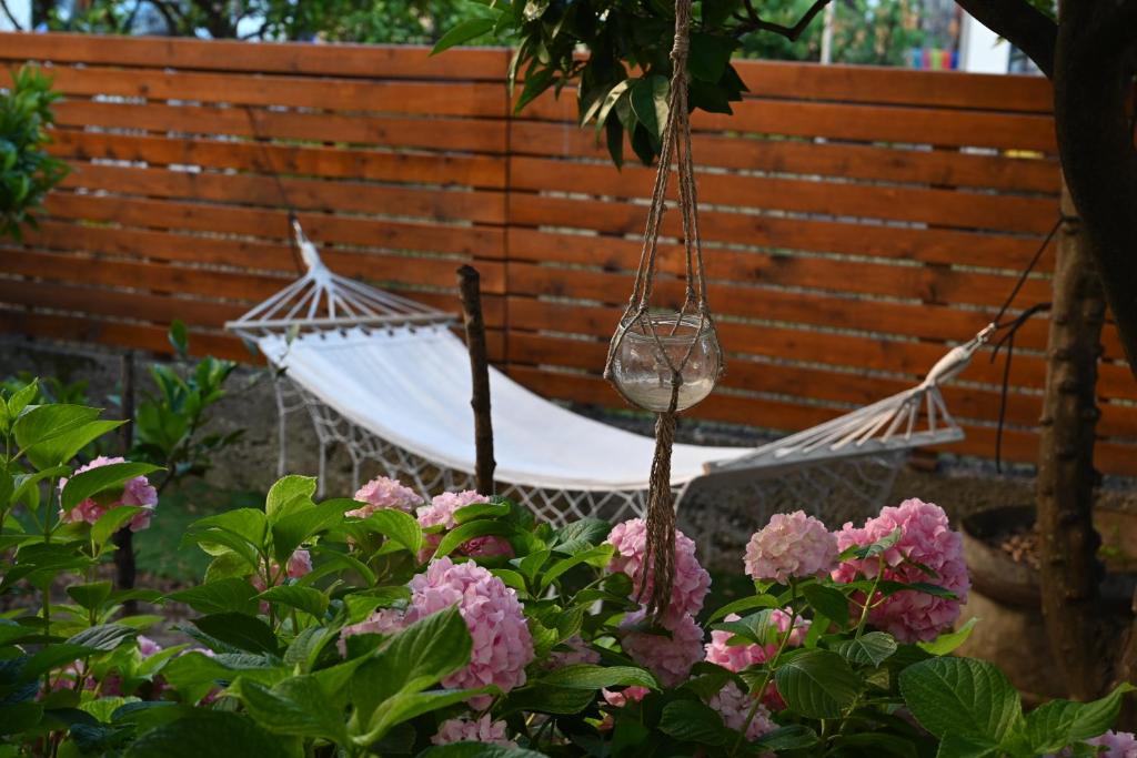 eine schwingende Hängematte im Garten mit rosa Blumen in der Unterkunft Hostel Center in Ulcinj