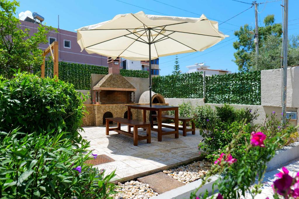 eine Terrasse mit einem Sonnenschirm, einem Tisch und einer Bank in der Unterkunft IDEAL HOUSE & APARTMENTS in Ksamil