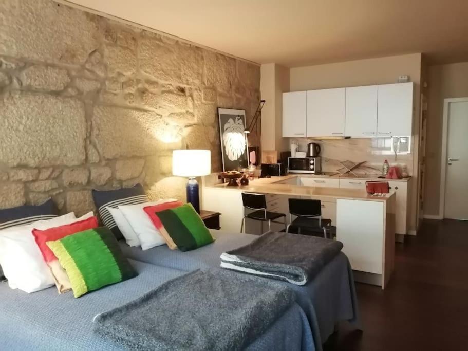 a bedroom with two beds with colorful pillows and a kitchen at No Porto in Porto