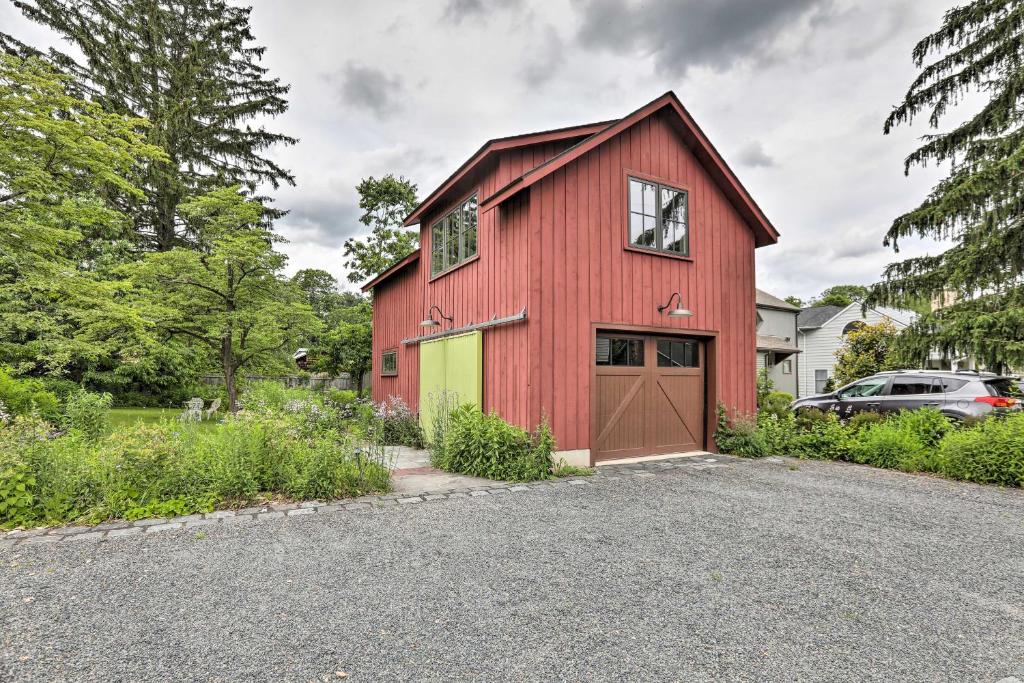 een rode schuur met een garage bij Barn-Like Studio Suite with Flowering Garden! 