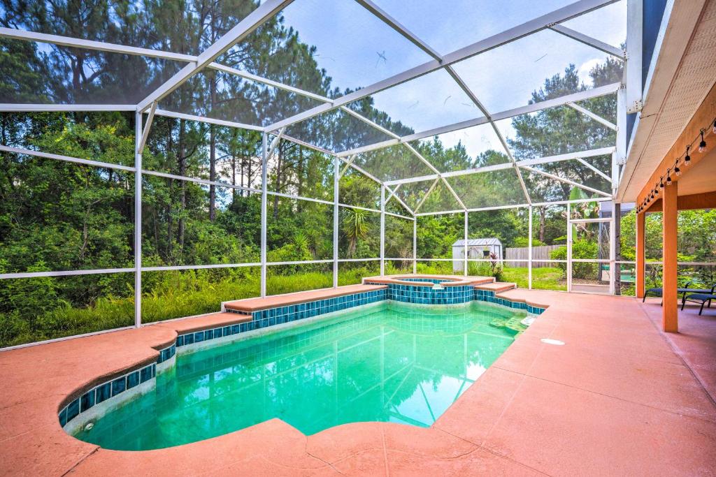 an indoor swimming pool in a glass house at Sunny Clermont Retreat with Pool 12 Mi to Disney! in Orlando