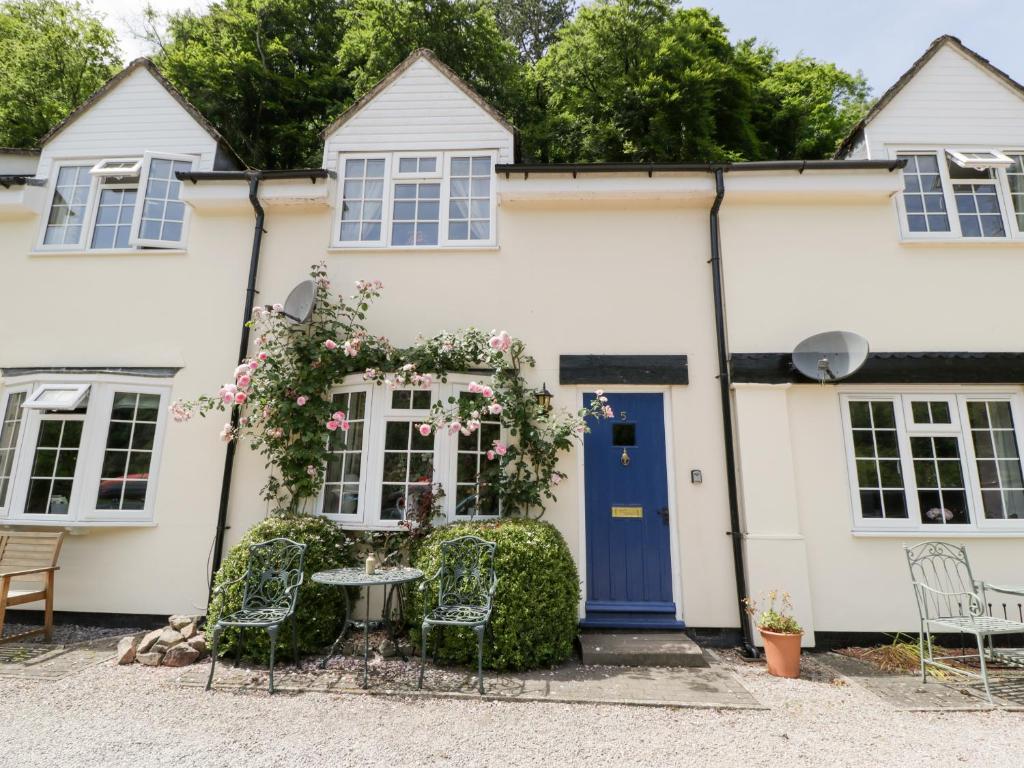 a white house with a blue door and chairs at 5 Wye Rapid Cottages in Ross on Wye