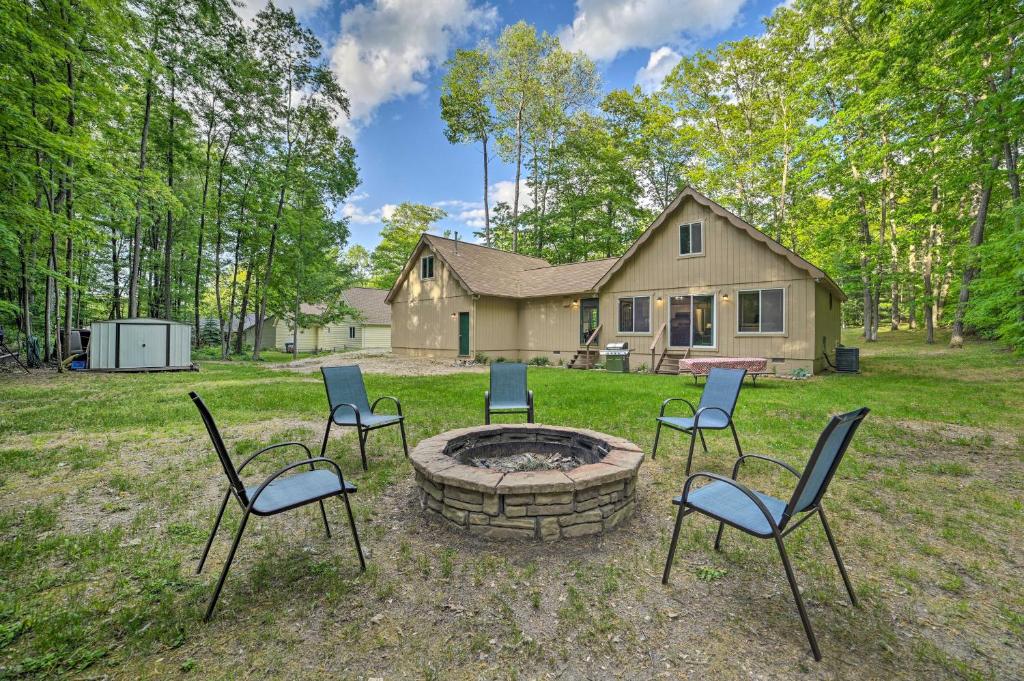 a group of chairs around a fire pit in front of a house at Higgins Lake Getaway - Boating, Fish, Golf, ATV! in Roscommon