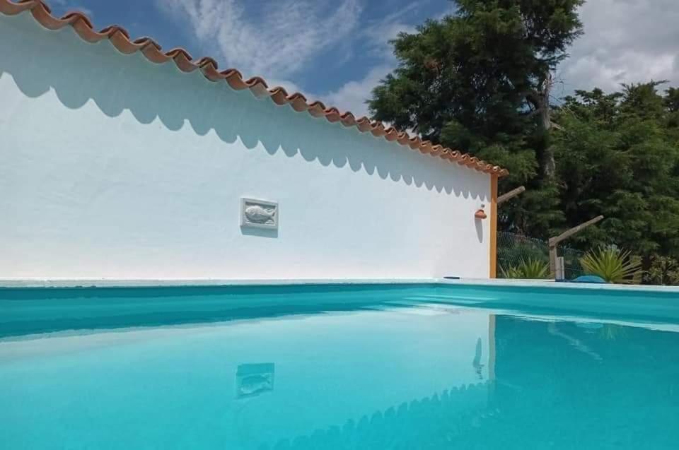 a swimming pool in front of a white wall at Casa do Lagar in Óbidos