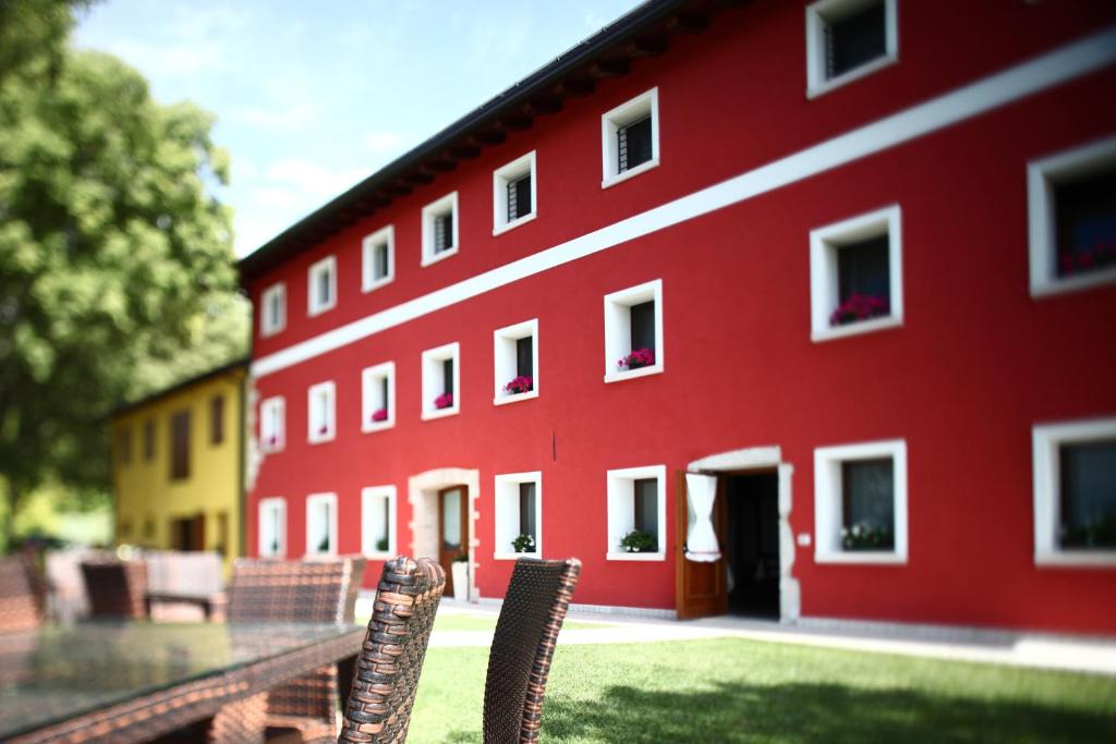 a red building with two chairs in front of it at Farm stay Al Pisoler in Caneva