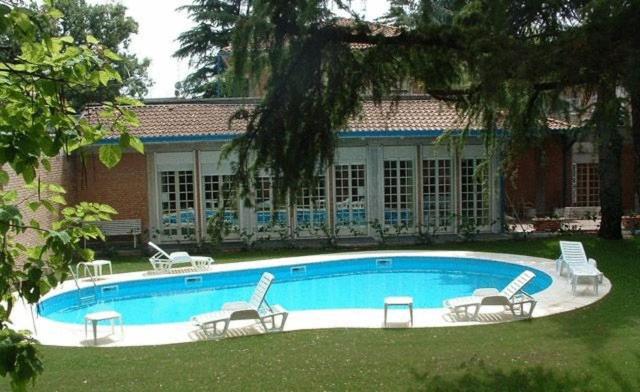 einen Pool mit Stühlen und ein Haus in der Unterkunft Park Hotel in Reggio nell'Emilia