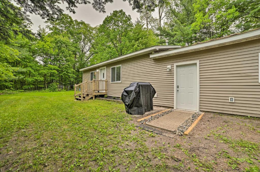 a house with a porch and a yard next to it at Vacation Rental In-Between Houghton and Higgins Lake in Houghton Lake
